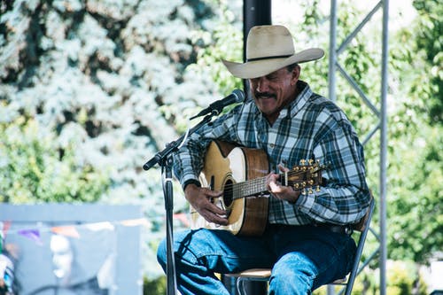 Man in a cowboy hat on stage playing a guitar