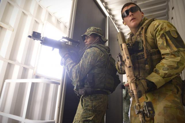 Soldiers from the Singapore Guards (L) and the 7th Australian Regiment clear a room during a dry run of an urban-based exercise at the Urban Operations Training Facility in Shoalwater Bay Training Area, Rockhampton, Australia November 9, 2014. The Straits Times/Mark Cheong/via REUTERS